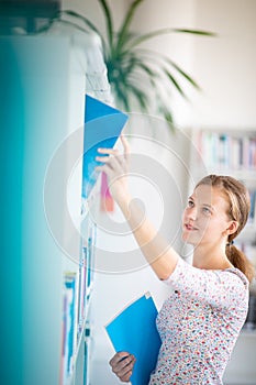 Cute female student with books in library