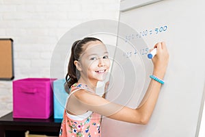 Cute Female Student Solving Sums On Flip Chart At Home