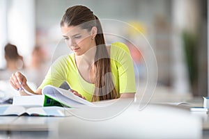 Cute female universit student with books in library