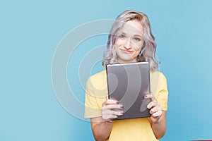Cute female in the yellow T-shurt holding tablet .