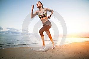 Cute fit girl running on beach at sunrise