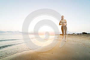 Cute fit girl running on beach at sunrise