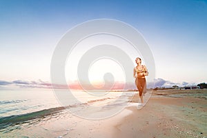 Cute fit girl running on beach at sunrise