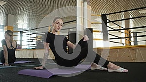 Cute fitness girl resting after exercise stretching muscles body in sports gym