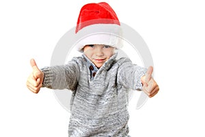 Cute five year old boy wearing a Santa Hat for Christmas with two thumbs up