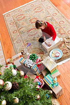 Cute five year old girl wrapping a Christmas gift