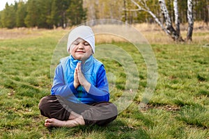 Cute four-year boy sits on a green grass
