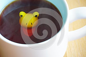 Cute frog figurine in the white mug with babyblue base