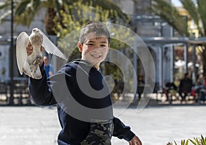 Cute and full of joy boy , is playing in the square , while feeding  the pigeons he finally managed to catch one . Enthusiasm is