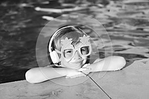 Cute fun kid face of little boy in funny sunglasses in pool in sunny day.