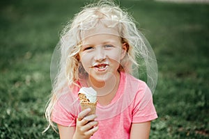 Cute funny adorable girl with dirty nose and milk moustaches eating licking ice cream from waffle cone. Child eating tasty sweet