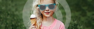 Cute funny adorable girl in sunglasses with dirty nose and moustaches eating ice cream from waffle cone. Happy cool hipster child