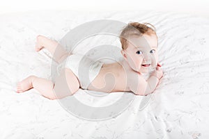 Cute funny baby with big beautiful eyes lying on white blanket