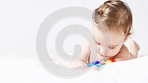 Cute funny baby girl in diaper playing with rattle on white bed in your room. portrait toddler. copy space