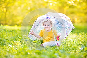 Cute funny baby girl playing in rain under umbrella