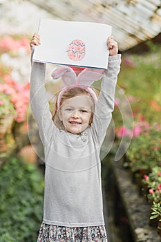 Cute funny girl with Easter bunny ears at garden. easter concept. Laughing child at Easter egg hunt