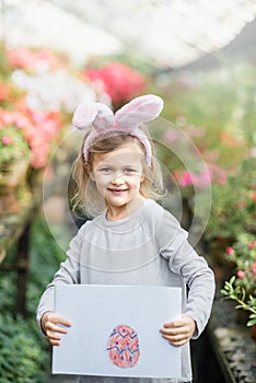 Cute funny girl with Easter bunny ears at garden. easter concept. Laughing child at Easter egg hunt