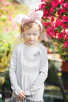 Cute funny girl with Easter bunny ears at garden. easter concept. Laughing child at Easter egg hunt
