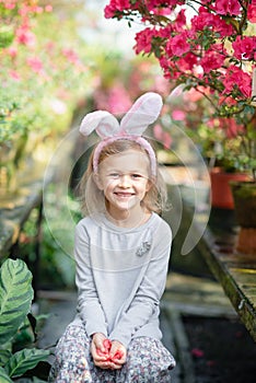 Cute funny girl with Easter bunny ears at garden. easter concept. Laughing child at Easter egg hunt