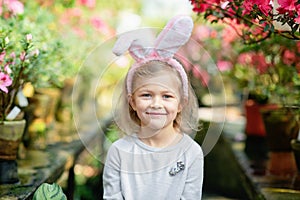 Cute funny girl with Easter bunny ears at garden. easter concept. Laughing child at Easter egg hunt