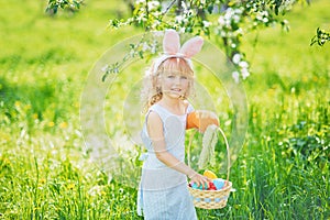 Cute funny girl with Easter eggs and bunny ears at garden. easter concept. Laughing child at Easter egg hunt