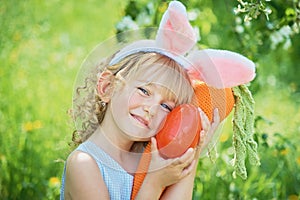 Cute funny girl with Easter eggs and bunny ears at garden. easter concept. Laughing child at Easter egg hunt