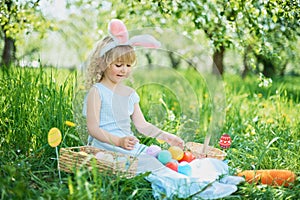 Cute funny girl with Easter eggs and bunny ears at garden. easter concept. Laughing child at Easter egg hunt