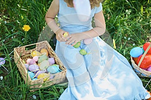 Cute funny girl with Easter eggs and bunny ears at garden. easter concept. Laughing child at Easter egg hunt