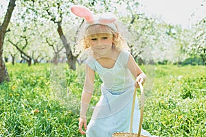 Cute funny girl with Easter eggs and bunny ears at garden. easter concept. Laughing child at Easter egg hunt