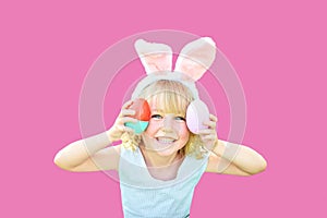 Cute funny girl with Easter eggs and bunny ears at garden. easter concept. Laughing child at Easter egg hunt