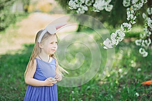 Cute funny girl with Easter eggs and bunny ears at garden. easter concept. Laughing child at Easter egg hunt