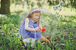 Cute funny girl with Easter eggs and bunny ears at garden. easter concept. Laughing child at Easter egg hunt