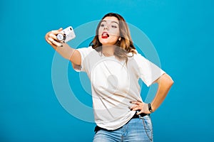 Cute funny girl student teenager makes selfie on a cell phone. Emotions and grimaces