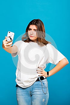 Cute funny girl student teenager makes selfie on a cell phone. Emotions and grimaces