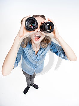 Cute funny girl with two pony tails looking thru photo lenses- wide angle