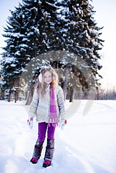 Cute funny kid girl 5-6 year old walk in snowy park over nature background outdoors