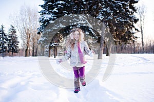 Cute funny kid girl 5-6 year old walk in snowy park over nature background outdoors