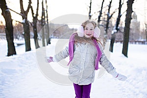 Cute funny kid girl 5-6 year old walk in snowy park over nature background outdoors.