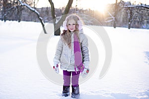 Cute funny kid girl 5-6 year old walk in snowy park over nature background outdoors.