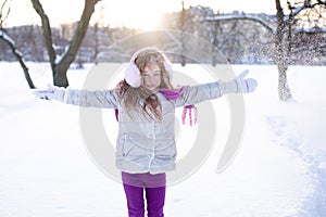 Cute funny kid girl 5-6 year old walk in snowy park over nature background outdoors.