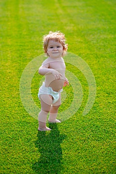 Cute funny laughing baby learning to crawl, having fun playing on the lawn watching summer in the garden. Happiness and