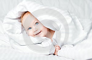 Cute and funny little baby smiling under white blanket. Copy spa