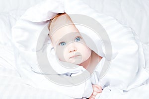 Cute and funny little baby smiling under white blanket. Copy spa