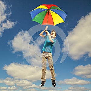 Cute funny little child in t-shirt flying in the sky with umbrella