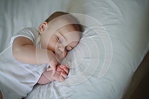 Cute funny newborn little boy peacefully sleeping on white sheets in bed or crib. Baby goods packaging template. Healthy