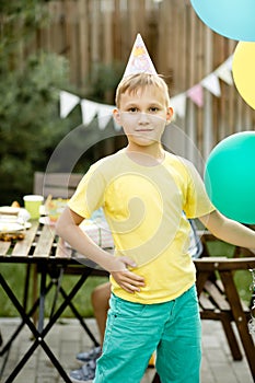 Cute funny nine year old boy celebrating his birthday with family or friends in a backyard. Birthday party. Kid wearing