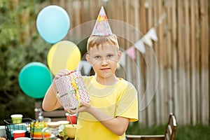 Cute funny nine year old boy celebrating his birthday with family or friends in a backyard. Birthday party. Kid wearing