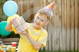 Cute funny nine year old boy celebrating his birthday with family or friends in a backyard. Birthday party. Kid wearing