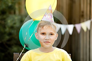 Cute funny nine year old boy celebrating his birthday with family or friends in a backyard. Birthday party. Kid wearing