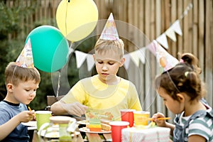 Cute funny nine year old boy celebrating his birthday with family or friends and eating homemade baked cake in a